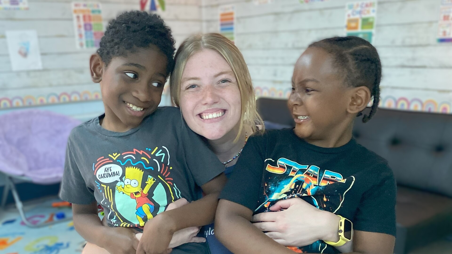 KidsLink staff member hugging two kids